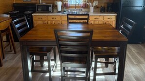 A cozy kitchen with wooden cabinets, a dining table with chairs, a refrigerator, and a microwave.