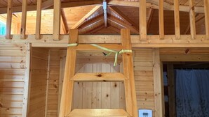 A wooden interior with a lofted sleeping area and a ladder leading to it.