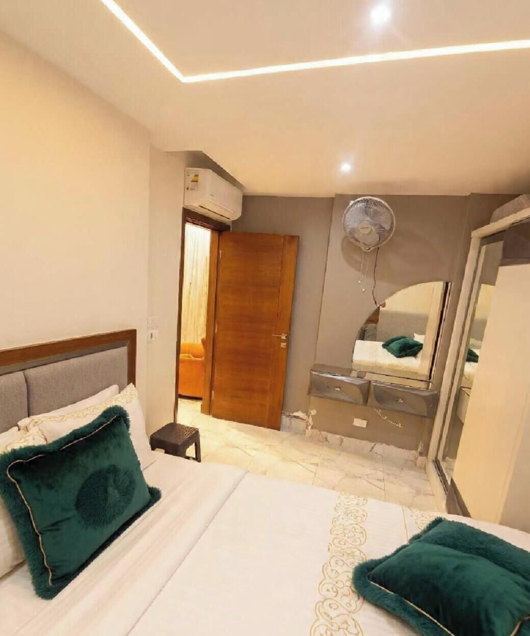 Une chambre d’hôtel équipée d’un lit, d’une table de chevet, d’une commode, d’un miroir et d’un ventilateur de plafond.