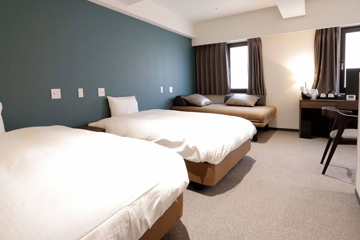 A hotel room with two beds, a desk, and a chair.