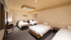 Ein Hotelzimmer mit zwei Betten, einem Schreibtisch, einem Stuhl, einem kleinen Tisch und einem Kleiderschrank.