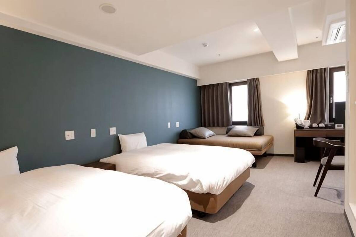 A hotel room with two beds, a desk, and a chair.