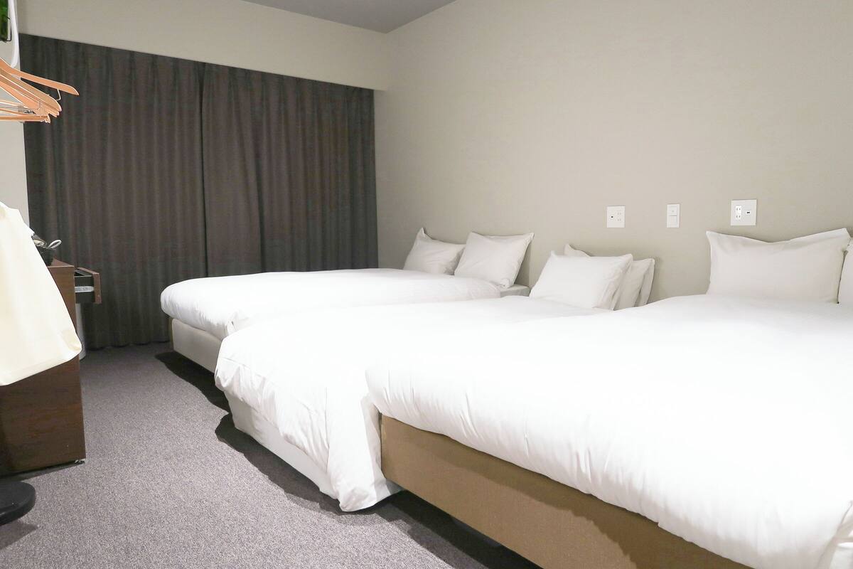 A hotel room with two beds, a desk, and a chair.