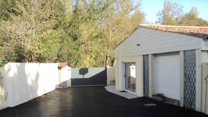 Un garage à l’extérieur blanc, doté d’une porte métallique et d’une allée noire.