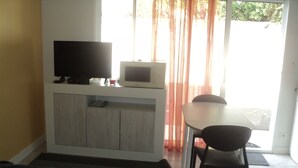 Un espace de vie comprenant un canapé, un téléviseur, un four à micro-ondes et une table à manger avec des chaises.