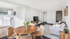 Een moderne woonkamer met een houten eettafel, een bank en een televisie.