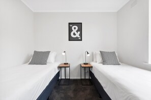 Een hotelkamer met twee eenpersoonsbedden, een zwart-wit kunstwerk aan de muur en een klein tafeltje tussen de bedden.