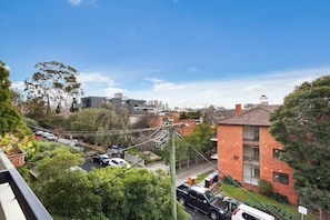 A residential area with modern and traditional buildings, a street with parked cars, and visible power lines.