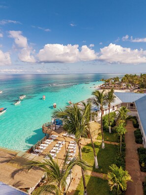 Um resort com praia, águas turquesa cristalinas e um píer com barcos.