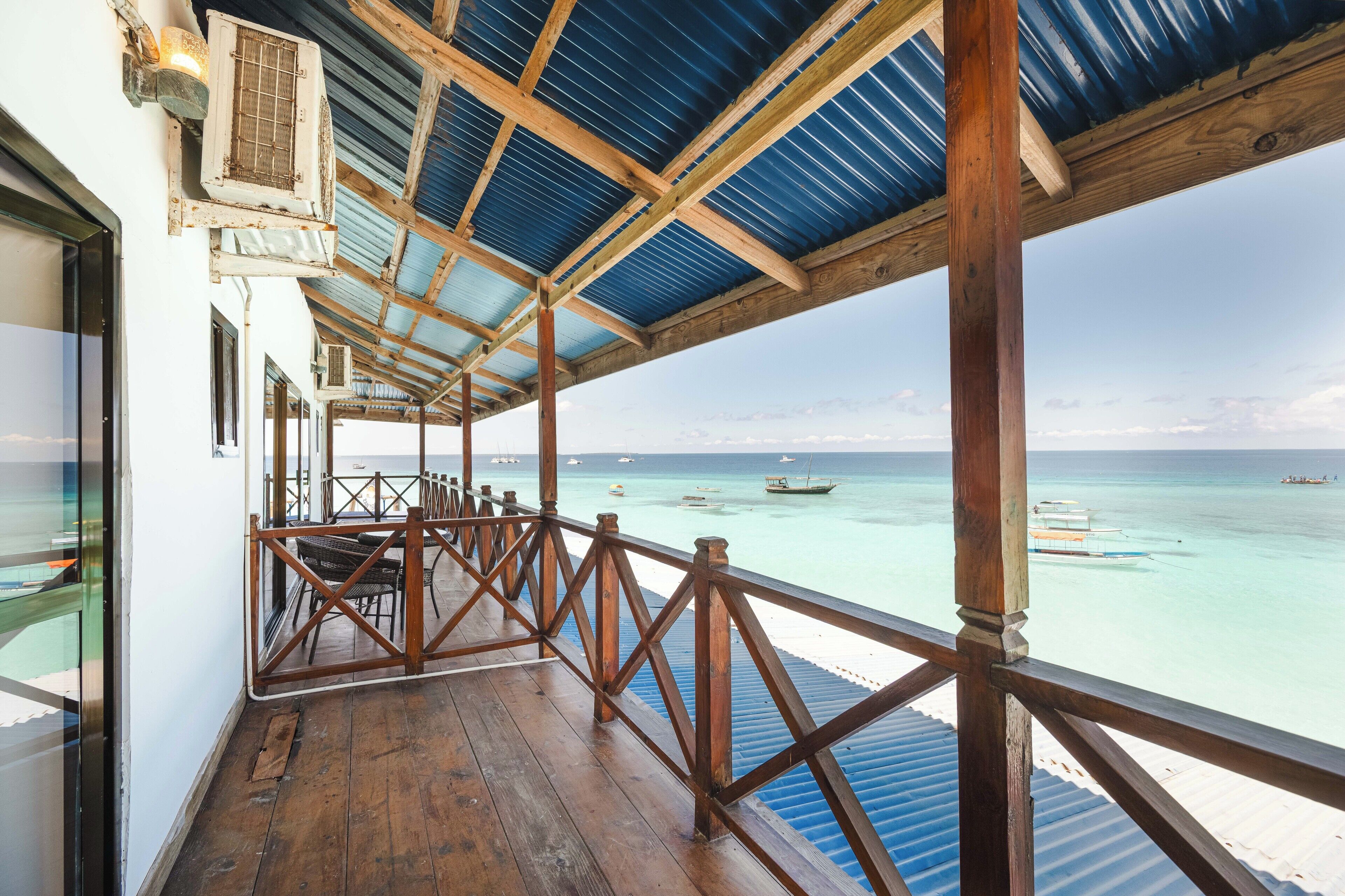 A wooden deck with a metal roof overlooking turquoise waters.