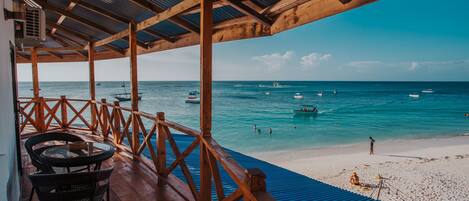 Una terraza de madera con vista a la playa y el océano.