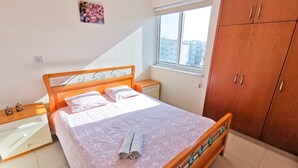A bedroom with a bed, nightstands, a window, and a wardrobe. - License to Chill Apartment (Larnaca)