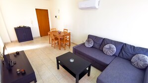 A living room with a sofa, coffee table, dining table, and chairs. - License to Chill Apartment (Larnaca)