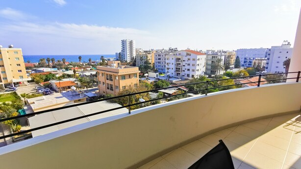 A balcony with a view of a cityscape, including buildings and a body of water. - License to Chill Apartment (Larnaca)