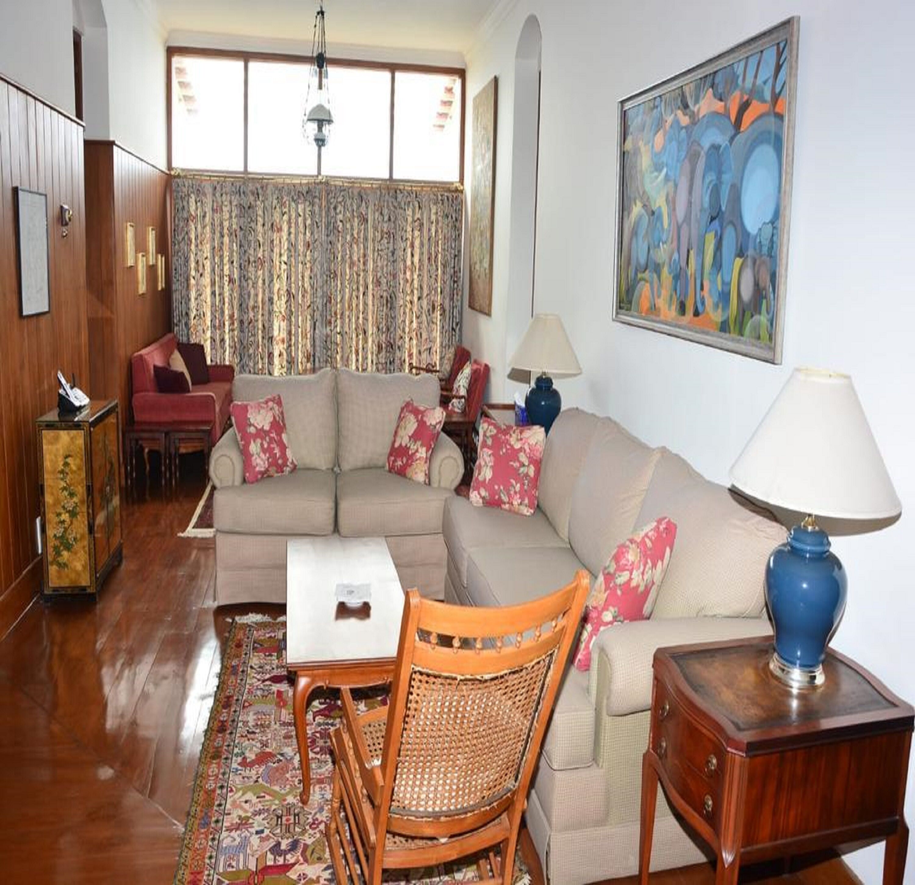 Un salon avec un canapé, une table basse, un fauteuil, une lampe et un tableau accroché au mur.