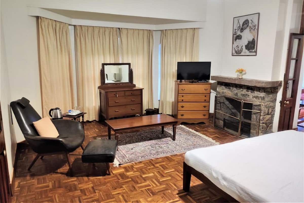 Ein Hotelzimmer mit einem Bett, einem Fernseher, einem Kamin, einem Schreibtisch, einem Sessel und einer Kommode.