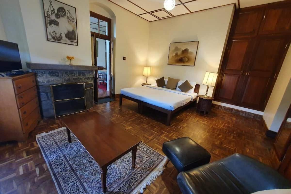 Ein Zimmer mit Bett, Schreibtisch, Stuhl, Sofa, Kamin und Holzboden.