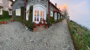Ein Haus aus Stein mit einem gewölbten Dach, einer zentralen weißen Tür und Blumentöpfen vor dem Eingang.