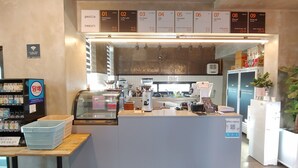 En bardisk i ett kafé, med en menytavla ovanför som visar olika sorters kaffe och te.