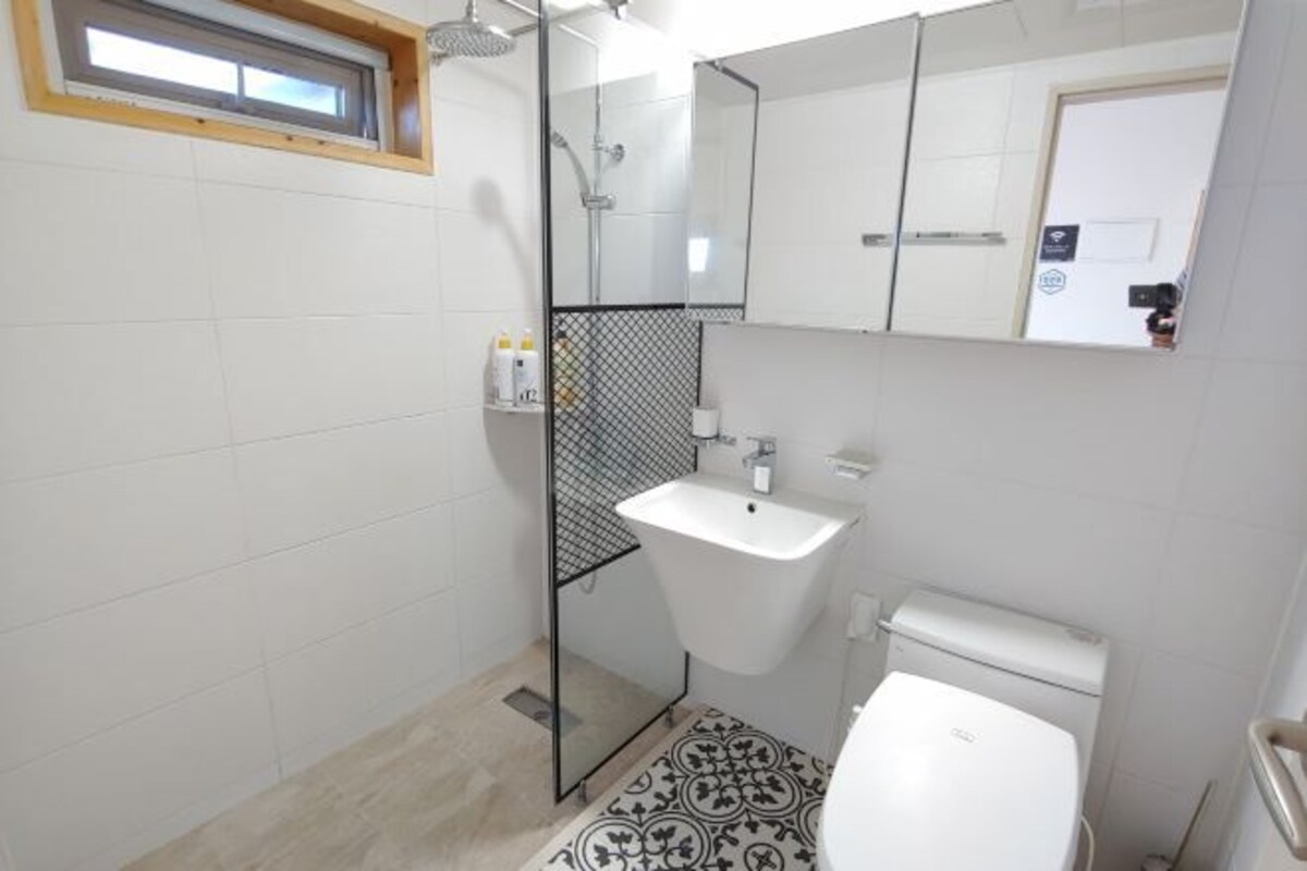 A small bathroom with a shower, a sink, and a toilet.