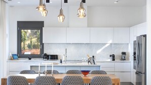 Een moderne keuken met witte kasten, een centraal eiland en een eethoek met patroonstoelen.