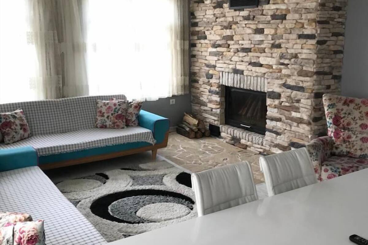 Ein Wohnzimmer mit einem Kamin aus Stein, einem blauen Sofa und einem weißen Tisch.