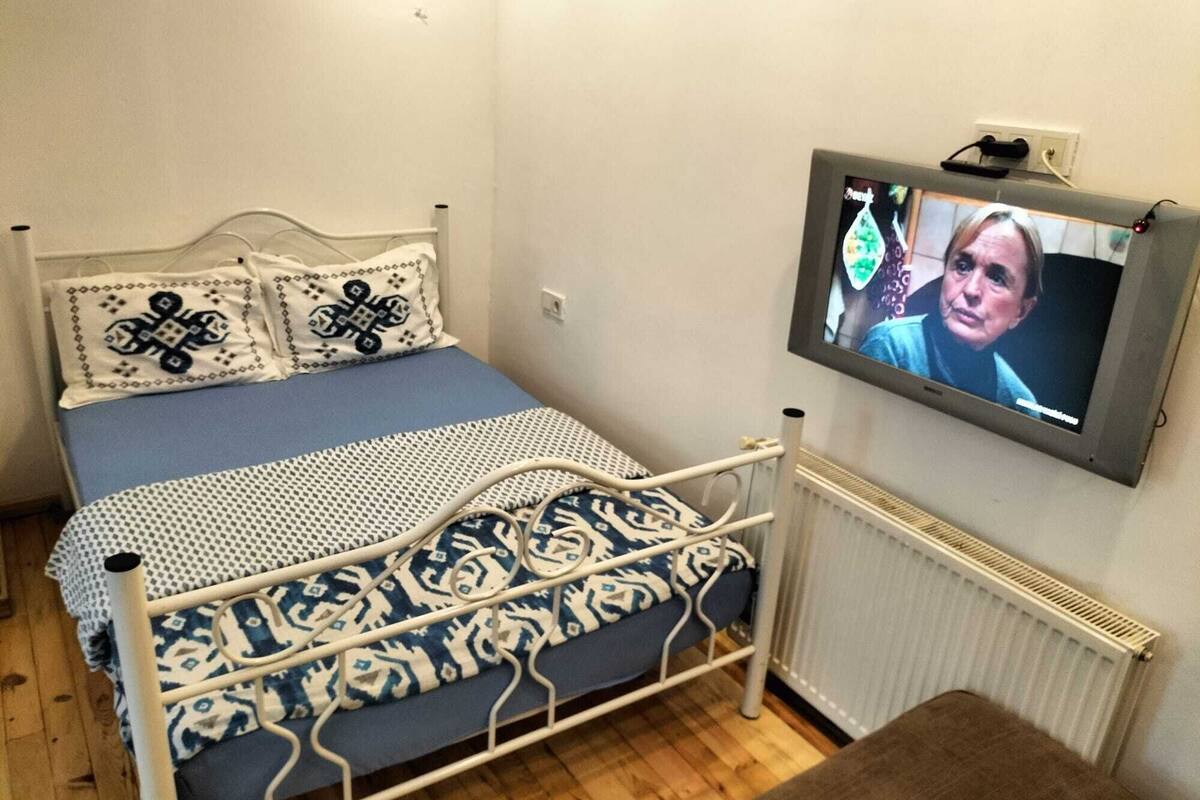 Ein Schlafzimmer mit Bett, Fernseher und Heizkörper.