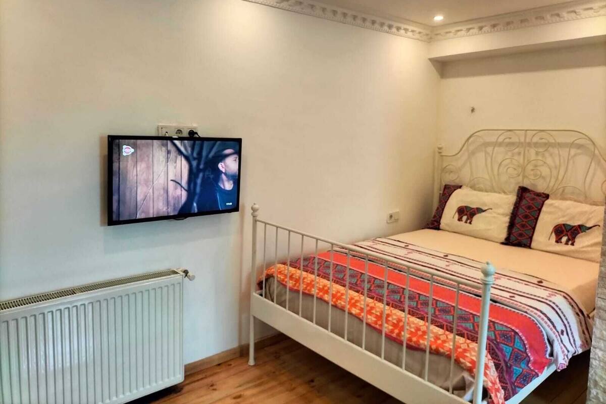 Ein Schlafzimmer mit einem Bett, einem an der Wand montierten Fernseher und einer Heizung.