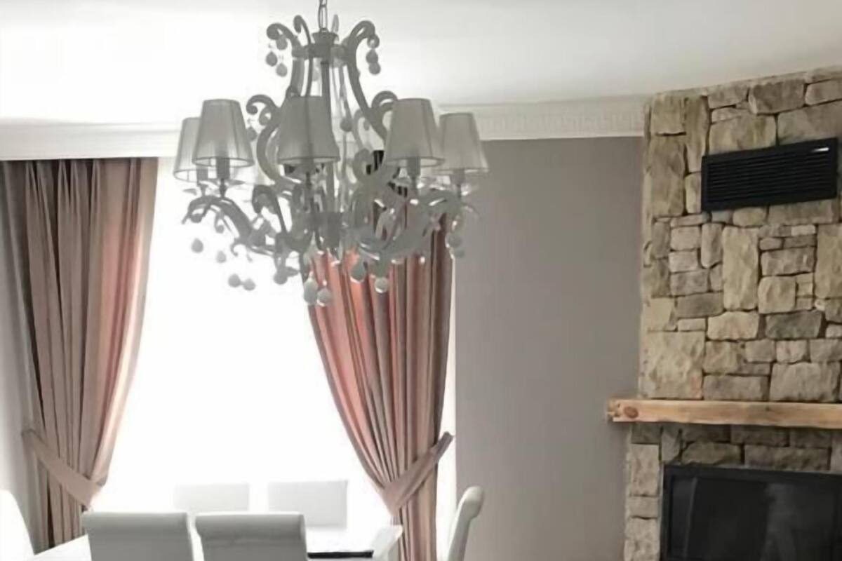 Ein Wohnzimmer mit Kamin aus Stein, weißen Möbeln und einem Chandelier.