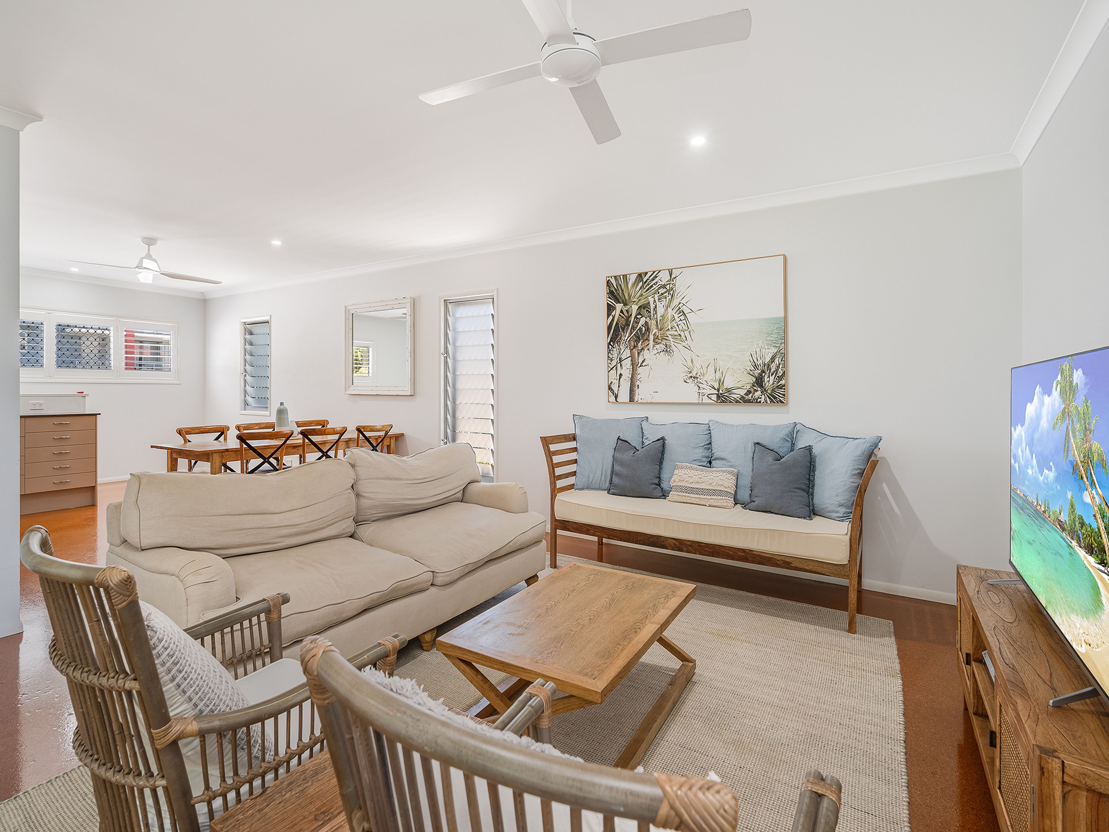A living room with a sofa, chairs, a coffee table, a TV, and a dining area with a table and chairs.