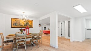 Un vaste espace dédié à la salle à manger, avec une table et des chaises en bois, un lustre et un grand tableau accroché au mur.