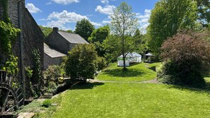 Escape to a serene garden oasis with a traditional water wheel and rustic architecture.