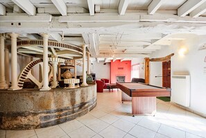 Relax in a spacious room with a high ceiling, featuring a billiards table and a fireplace.
