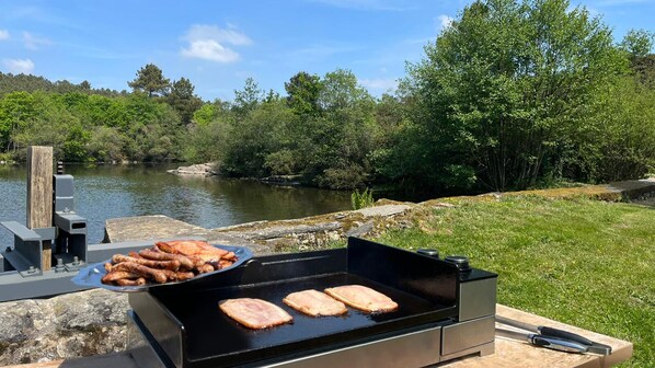 A grill with sausages and steaks cooking outdoors near a body of water. - MOULIN Menhirs & nature reserve (Saint-Just)