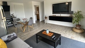 Una sala de estar moderna con un sofá, una mesa de centro y un televisor de pantalla plana montado en la pared.