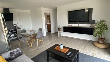 A modern living room with a sofa, coffee table, and a flat-screen TV mounted on the wall.