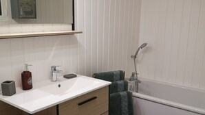 Une salle de bain moderne avec un meuble-lavabo blanc, un grand miroir, une douche et un tapis de bain noir.