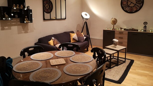 Un salon moderne avec une table à manger ronde, un canapé foncé et des horloges décoratives.