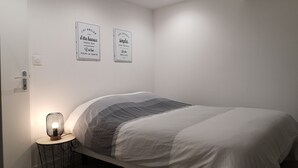 Une chambre à coucher avec un lit, une table de chevet avec une lampe et deux panneaux décoratifs fixés au mur.