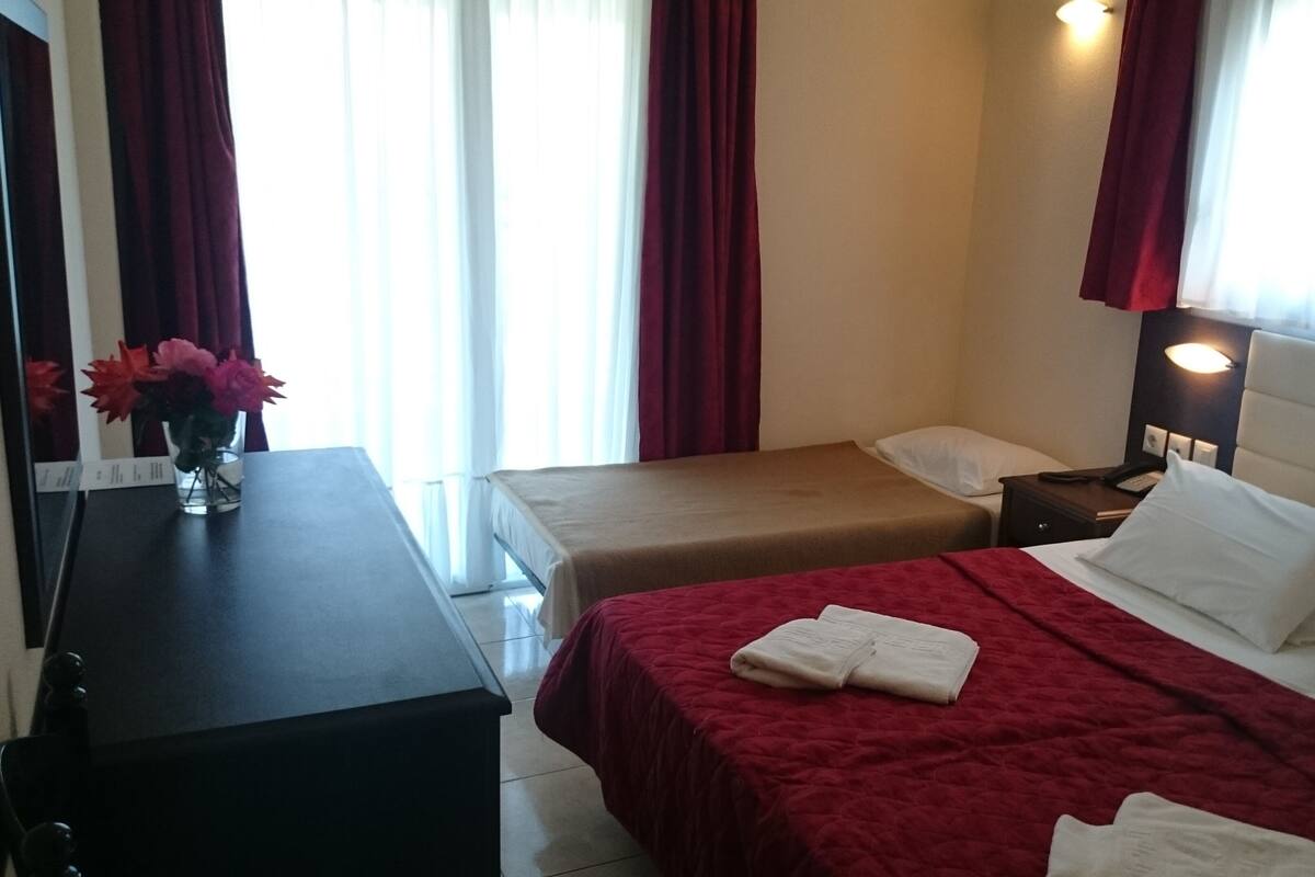 A hotel room with two beds, a desk, and a nightstand.