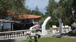 A garden with a white archway, a pergola, and a view of the sea. - Kassandra Bay (Kassandra)