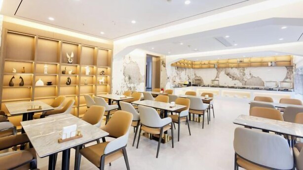A modern restaurant with marble-topped tables and chairs, warm lighting, and decorative wall art. - JiHe Hotel (Jiaozuo Railway Station Puji Road) (Jiaozuo)