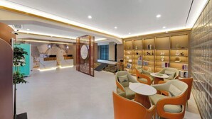 A modern lobby with a reception desk, seating area, and a wall of decorative items. - JiHe Hotel (Jiaozuo Railway Station Puji Road) (Jiaozuo)