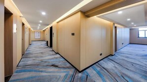 A hotel corridor with a carpeted floor, wooden panel walls, and recessed lighting. - JiHe Hotel (Jiaozuo Railway Station Puji Road) (Jiaozuo)