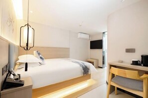 A modern hotel room with a large bed, bedside table, and a desk with a chair. - JiHe Hotel (Jiaozuo Railway Station Puji Road) (Jiaozuo)