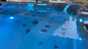 Ein Whirlpool mit mehreren Düsen, umgeben von einem Gartenblick.