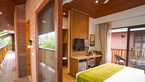 A hotel room with a bed, desk, TV, and balcony. - TreeHouse MARS Beach Cottages (Calangute)
