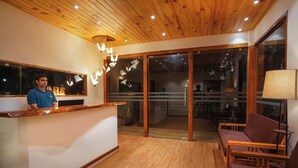 A reception area with a wooden ceiling, a reception desk, and a seating area with wooden chairs. - TreeHouse MARS Beach Cottages (Calangute)