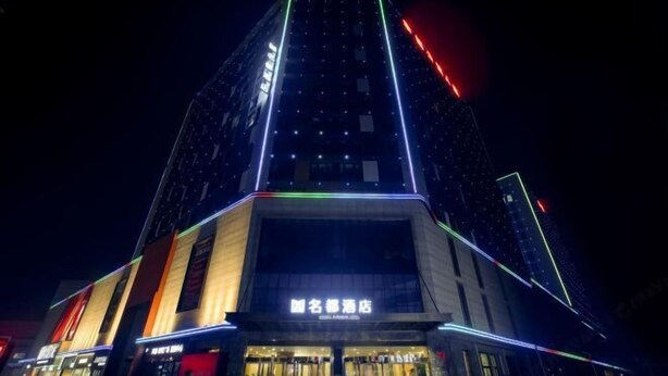 A modern hotel with a prominent entrance and a tall building with illuminated lines. - Mingdu Hotel (Wuyang)