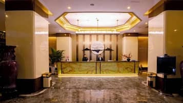 A hotel reception area with a marble floor, a reception desk, and a large decorative globe.